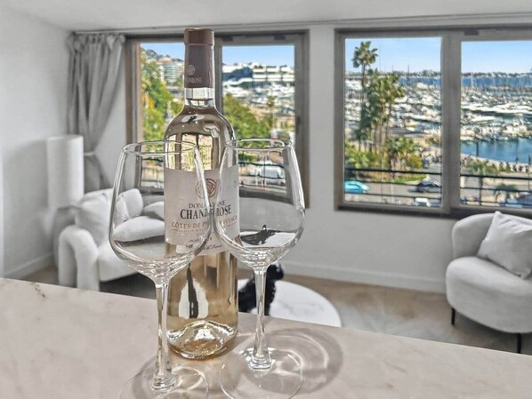 Eine Flasche Domaine Chandon Champagner und zwei Gläser auf einem Tisch mit Blick auf einen Jachthafen und Gebäude.
