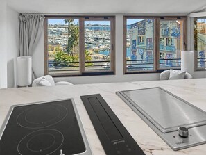 Eine moderne Küche mit Blick auf einen Yachthafen, großen Fenstern und einer Marmorarbeitsplatte.