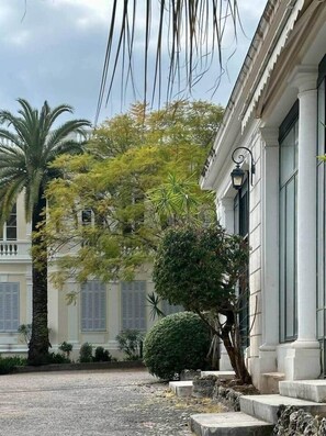 Un edificio de fachada blanca, con un balcón y un patio empedrado.