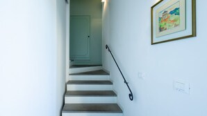 Eine Treppe mit Handlauf, eine Tür am oberen Ende und ein gerahmtes Bild an der Wand.