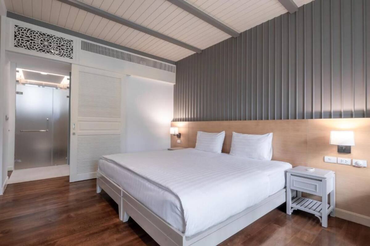 A hotel room with a large bed, a bedside table, a wall-mounted lamp, and a wardrobe with a sliding door.
