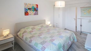 A bedroom with a bed, bedside table, lamp, wardrobe, and a world map on the wall. - Vacation home Canepa by Interhome (Sori)