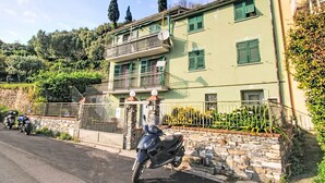 A two-story building with a balcony, stone wall, and parked motorcycles. - Vacation home Canepa by Interhome (Sori)