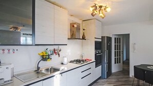 A modern kitchen with white cabinets, a gas stove, a refrigerator, and a dining area with a table and chairs. - Vacation home Canepa by Interhome (Sori)
