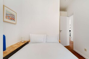 A hotel room with a bed, a nightstand, a lamp, and a framed picture on the wall. - Discover Lisbon from São Vicente Base (Lisbon)
