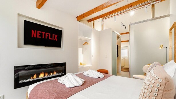 Une chambre d’hôtel équipée d’un lit, d’une cheminée, d’un téléviseur fixé au mur et d’une porte donnant accès à une salle de bain.