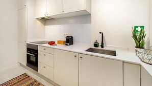 Une cuisine moderne avec des armoires blanches, un évier en acier inoxydable et un four encastré.