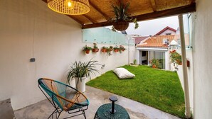 Une terrasse couverte avec une plante suspendue, une chaise et une petite table.