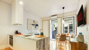 Uma cozinha moderna com ilha de mármore, área de refeições com móveis de madeira e uma janela grande.