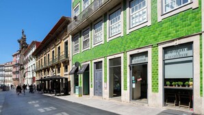 Rua com edifícios, incluindo uma vitrine verde com um letreiro.