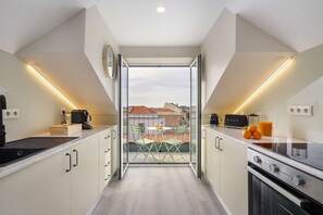 Eine moderne Küche mit Kochinsel, einem Essbereich mit Tisch und Stühlen sowie Blick auf die Stadt durch eine Glastür.