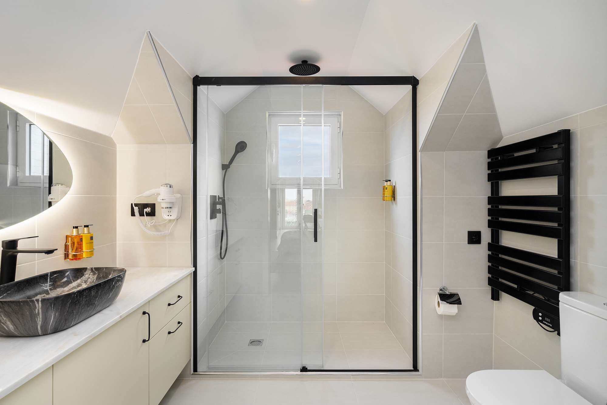 Een moderne badkamer met een douchecabine van glas, een toilet, een wastafel met een marmeren kom en een handdoekhouder.