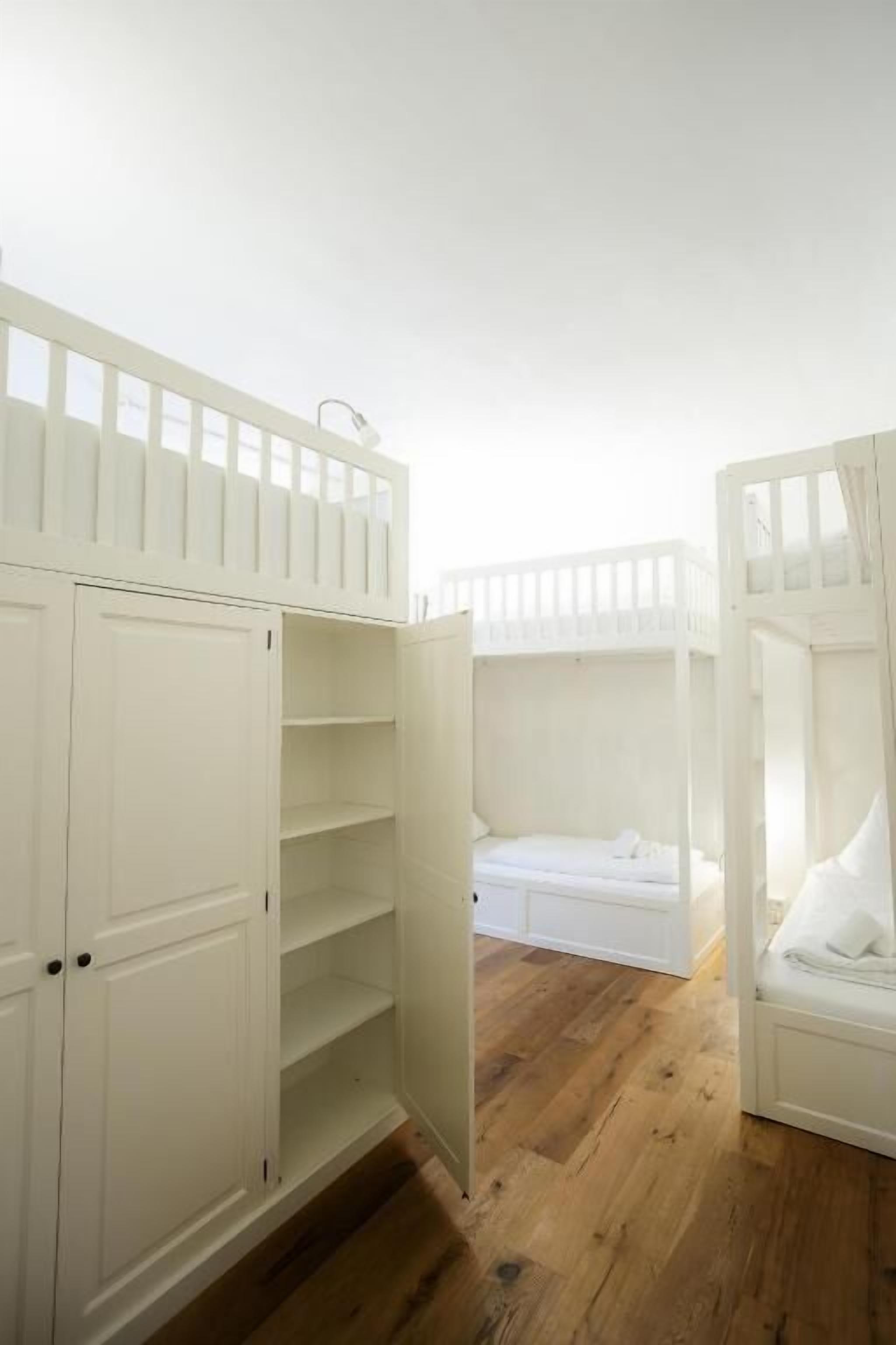 Una habitación con literas, un armario y un pequeño rincón de descanso.