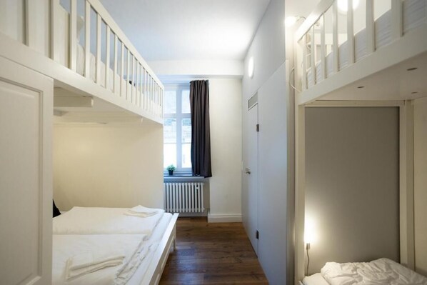 A hotel room with a bunk bed, a window with curtains, a radiator, and a door. - heimatgleis (Brilon)