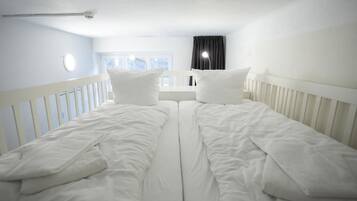 A twin room with two beds, a window with curtains, and a white railing.
