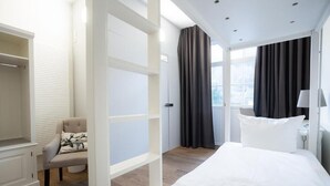 A hotel room with a bed, a chair, a wardrobe, and a window with curtains. - heimatgleis (Brilon)