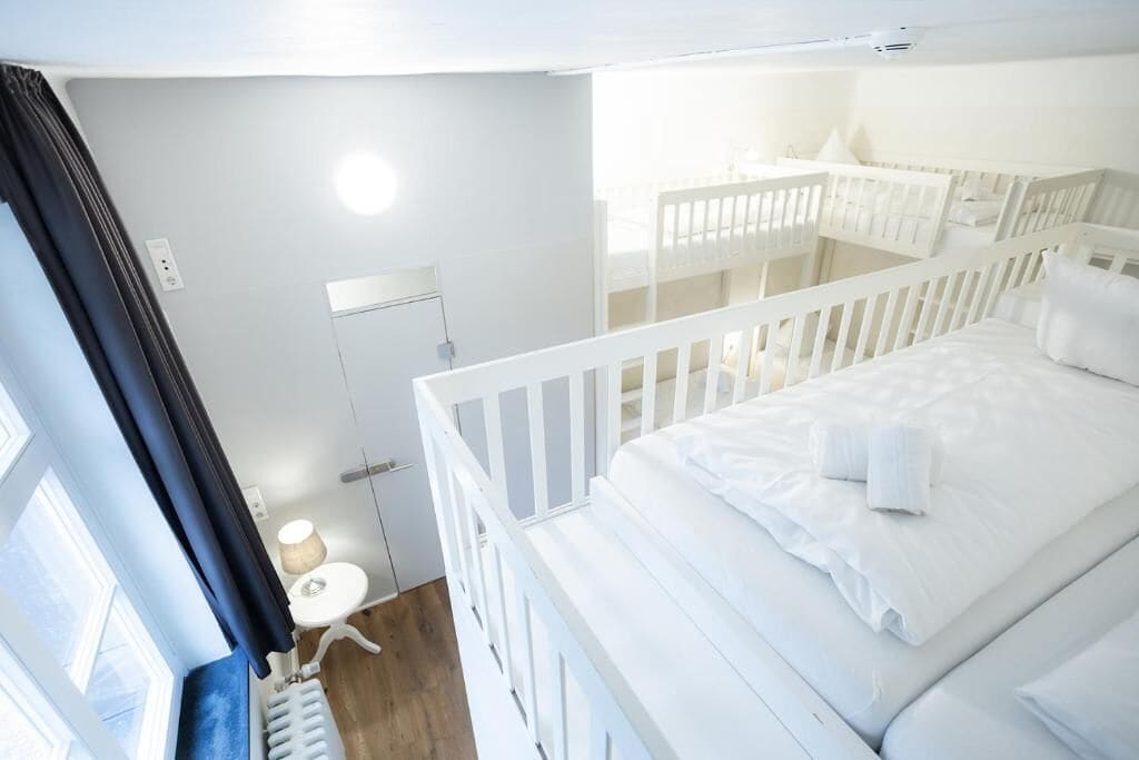 A white room with a bed, a small table, and a window.