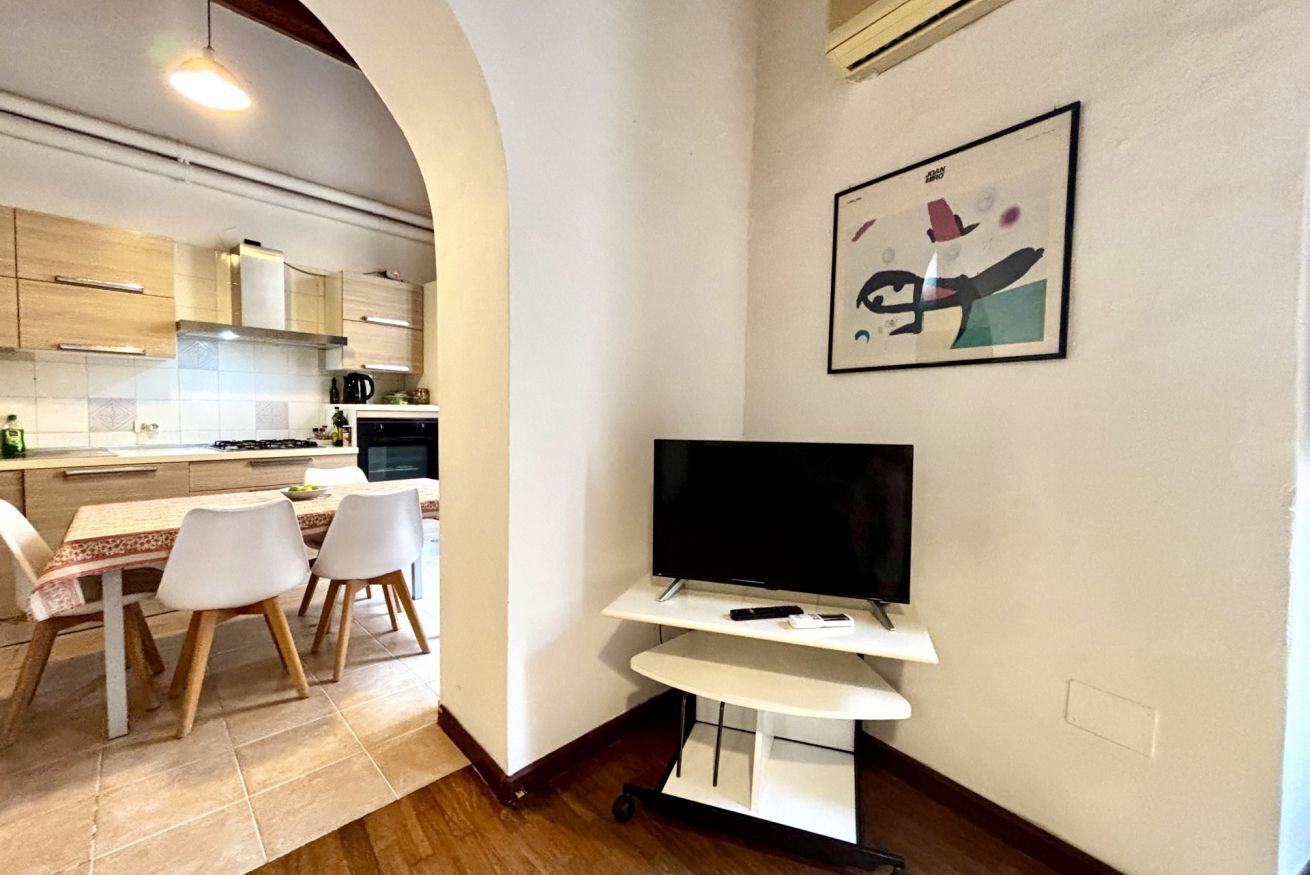 Una cucina moderna con zona pranzo, una TV a schermo piatto su un mobile e un'opera d'arte incorniciata al muro.