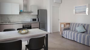 Eine moderne Küche mit weißen Schränken, einem Esstisch und einem gestreiften Sofa.