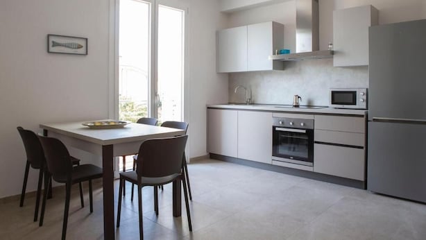Eine moderne Küche mit Esstisch, Stühlen, Schränken, einer Mikrowelle, einem Backofen und einem Kühlschrank.