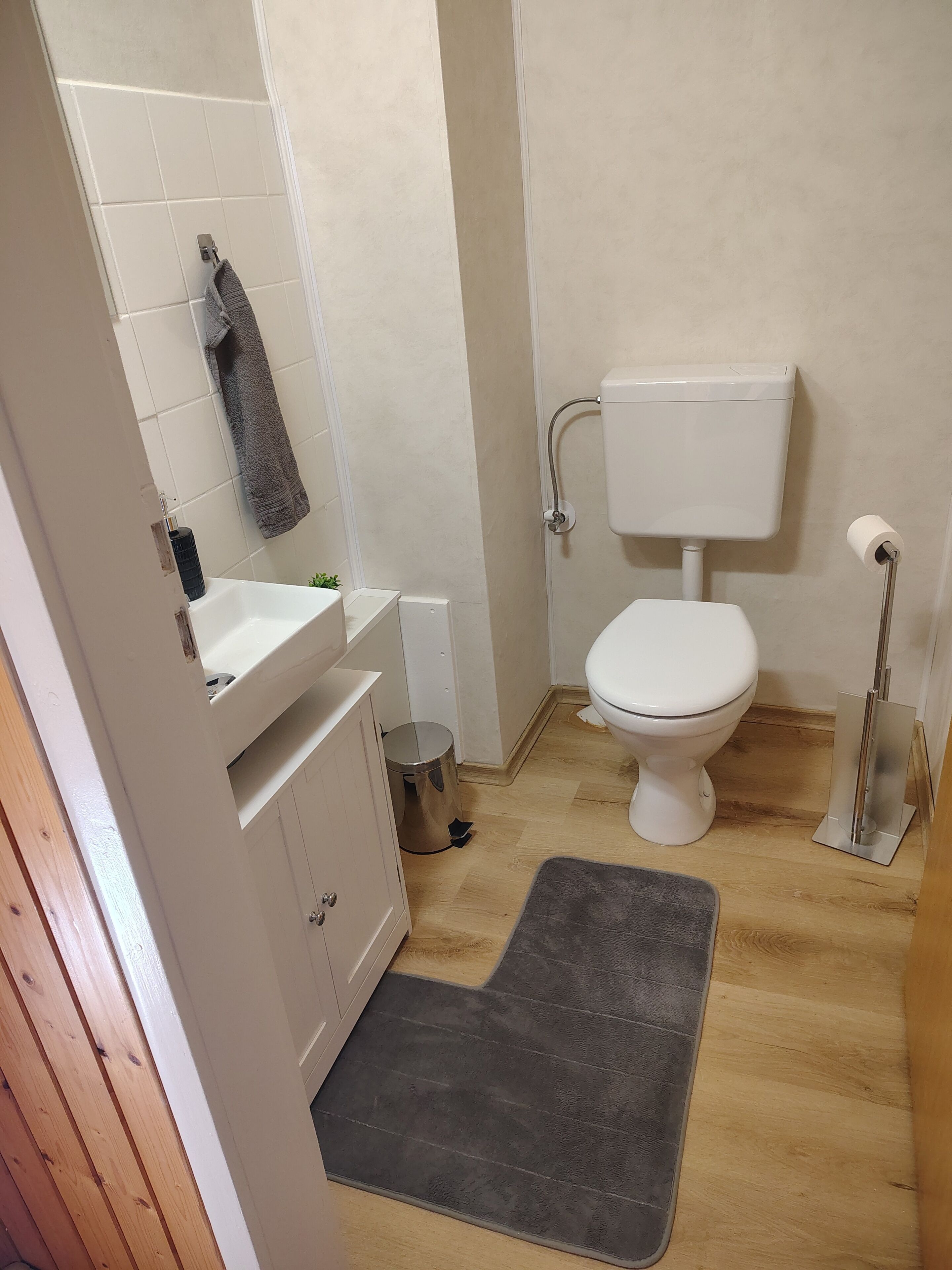 A bathroom with a toilet, sink, and a small trash bin.
