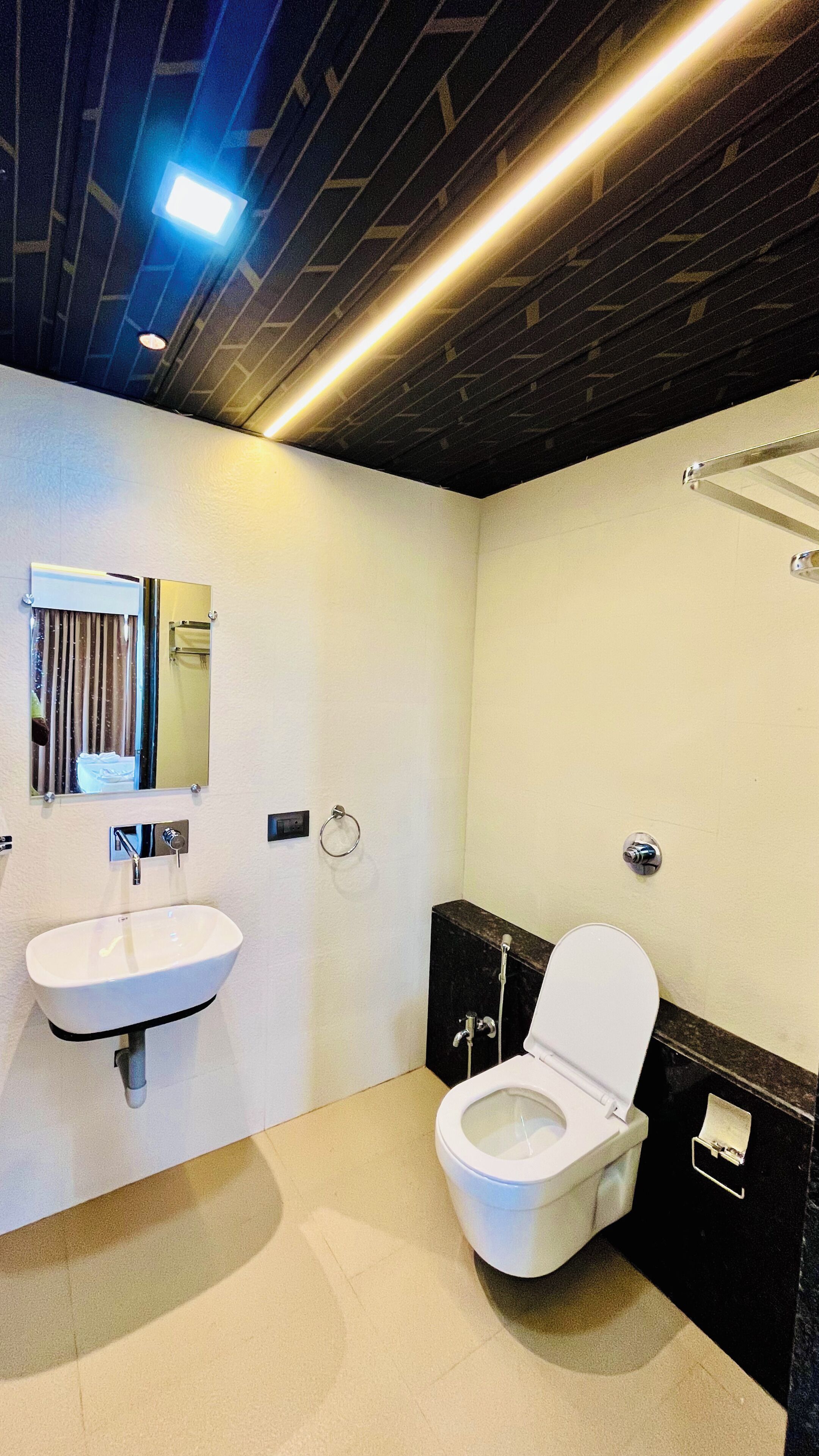 A bathroom with a white sink, a toilet, a mirror, and a towel rack.