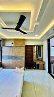 A hotel room with a bed, ceiling fan, bedside table, and a view of the outside.