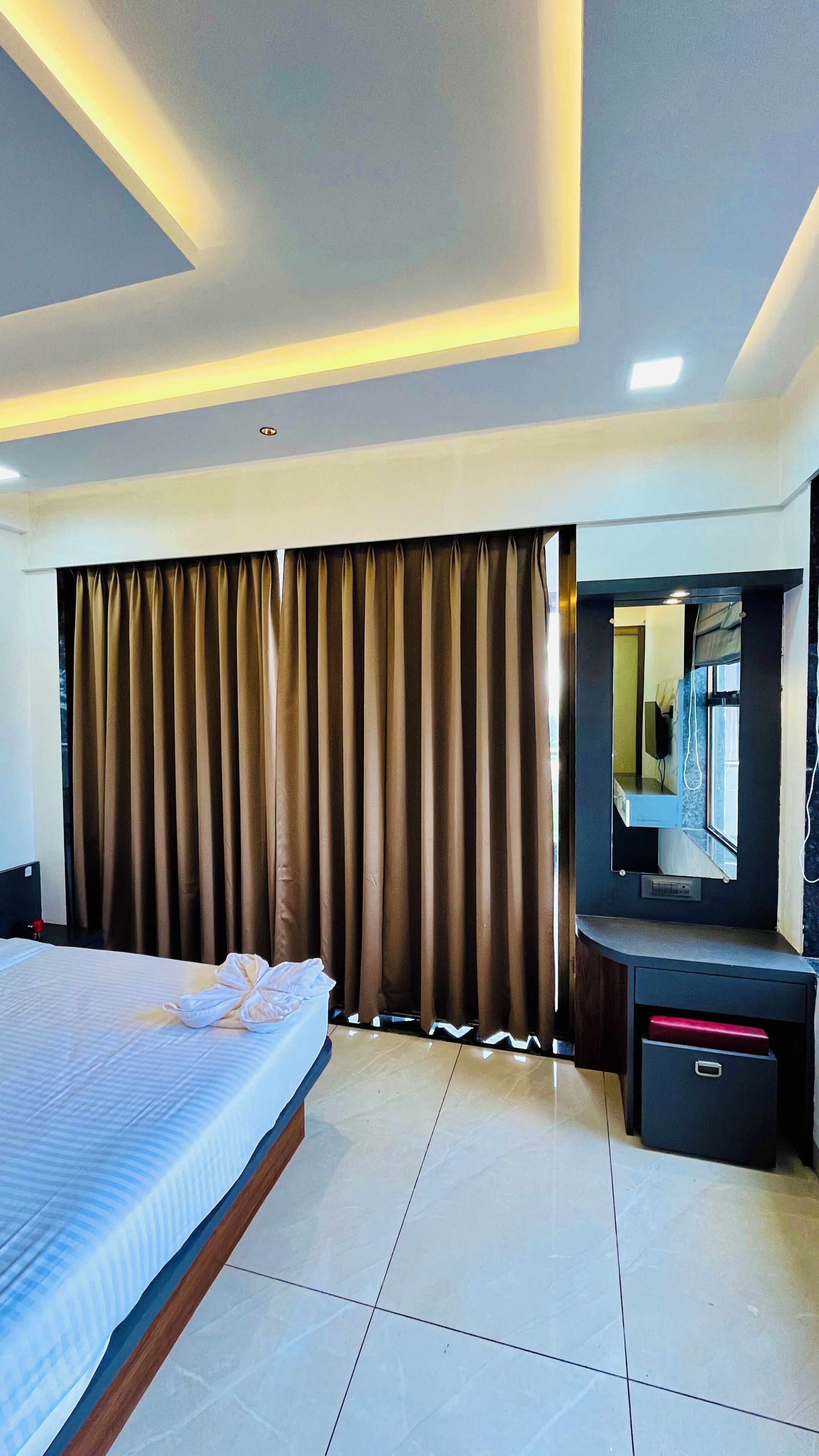 Une chambre d’hôtel avec un lit, un bureau doté d’un miroir et des rideaux.