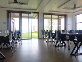 A conference room with a glass partition, modern chairs, and a ceiling fan.