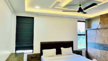 A modern bedroom with a bed, bedside tables, a bench, a ceiling fan, and a window.