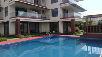 A multi-story hotel with a swimming pool, balconies, and a covered outdoor area.