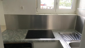 A kitchen with a stainless steel countertop, a dishwasher, and a window with a view of the outside. - Casa Ines - 1 1/2 Zimmer Whg Terrasse mit Seesic by Interhome (Magadino)