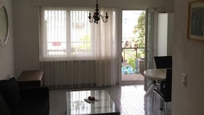 A room with a large window, a chandelier, a dining table, and a kitchen area. - Casa Ines - 1 1/2 Zimmer Whg Terrasse mit Seesic by Interhome (Magadino)