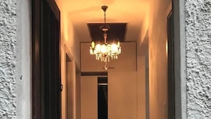 Un couloir orné d’un lustre, d’un banc et d’un tapis sur lequel est inscrit un texte.