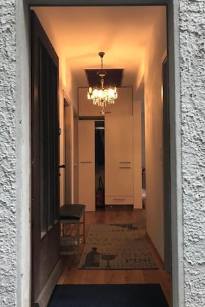 Ein Flur mit einer Chandelüstere, einer Bank und einem Teppich mit Text.