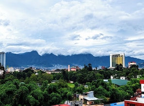 Un paisaje urbano con edificios, una cordillera y un cielo nublado.