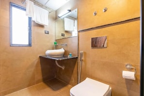 Un baño con lavamanos, espejo, inodoro y perchero para toallas.
