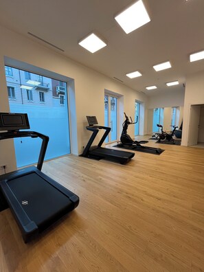 Ein Fitnessraum mit Laufbändern, Ergometer und einer Spiegelwand.