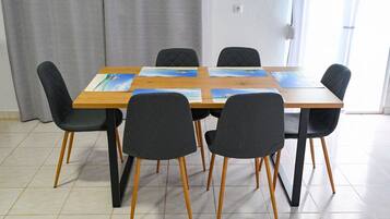 Zona pranzo con tavolo in legno e sei sedie nere, ognuna con gambe in legno.