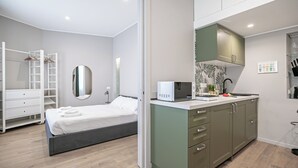 A modern bedroom with a bed, a wardrobe, and a kitchenette with a microwave. - Italianway Comfort - Sottocorno 17 (Milan)