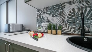 A kitchen with a modern microwave, a sink, and a countertop with fresh produce and potted herbs. - Italianway Comfort - Sottocorno 17 (Milan)