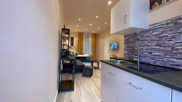 Een moderne keuken met een steen rugpaneel, een ingebouwde oven en een zithoek met een bank en tafel.