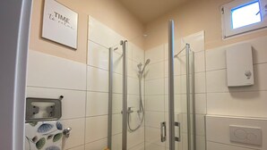 Een moderne badkamer met een douche met glazen wand, een toilet en een houten plank.