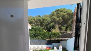 Blick durch eine Tür in einen Garten mit Pool, Gymnastikmatten und einer weißen Skulptur.
