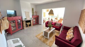 Ein Wohnzimmer mit rotem Sofa, Couchtisch, Fernseher und Kamin.