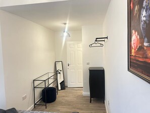 Ein Flur mit Spiegel, Pendelleuchte, Tür und einem gerahmten Gemälde an der Wand.