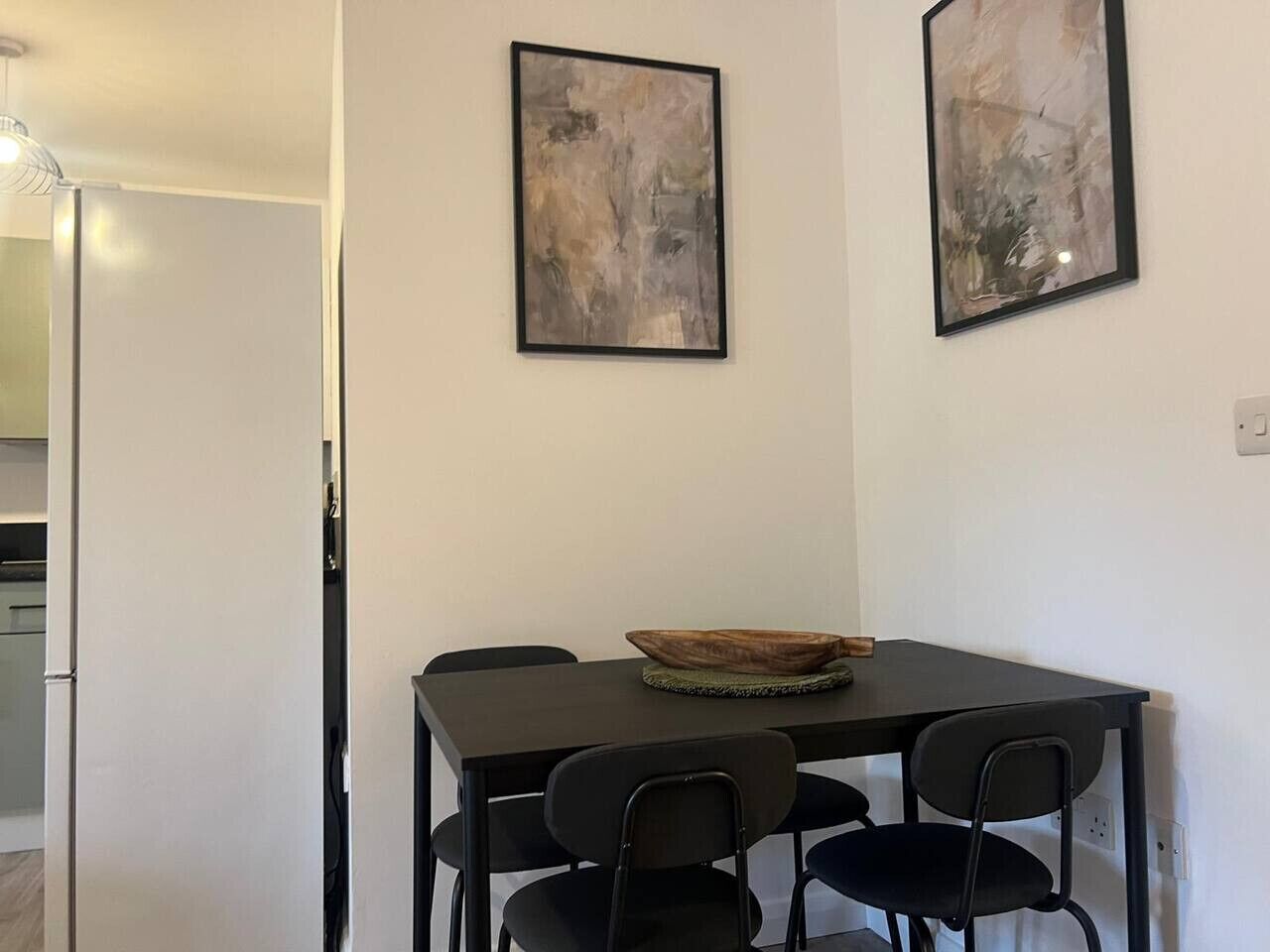 Ein Essbereich mit einem Tisch, Stühlen und zwei abstrakten Bildern an der Wand.