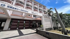 A multi-story building with a sign indicating it is a youth hostel. - Enagic OKinawaInternational Youth Hostel (Naha)