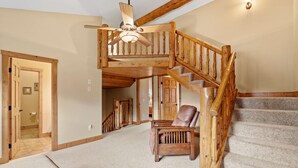 Eine Holztreppe mit Deckenventilator, einem Ledersessel und einem Teppichboden.