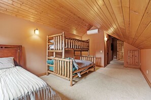 Una habitación con literas, una cama individual, techo de madera y un pasillo que conduce a otra habitación.